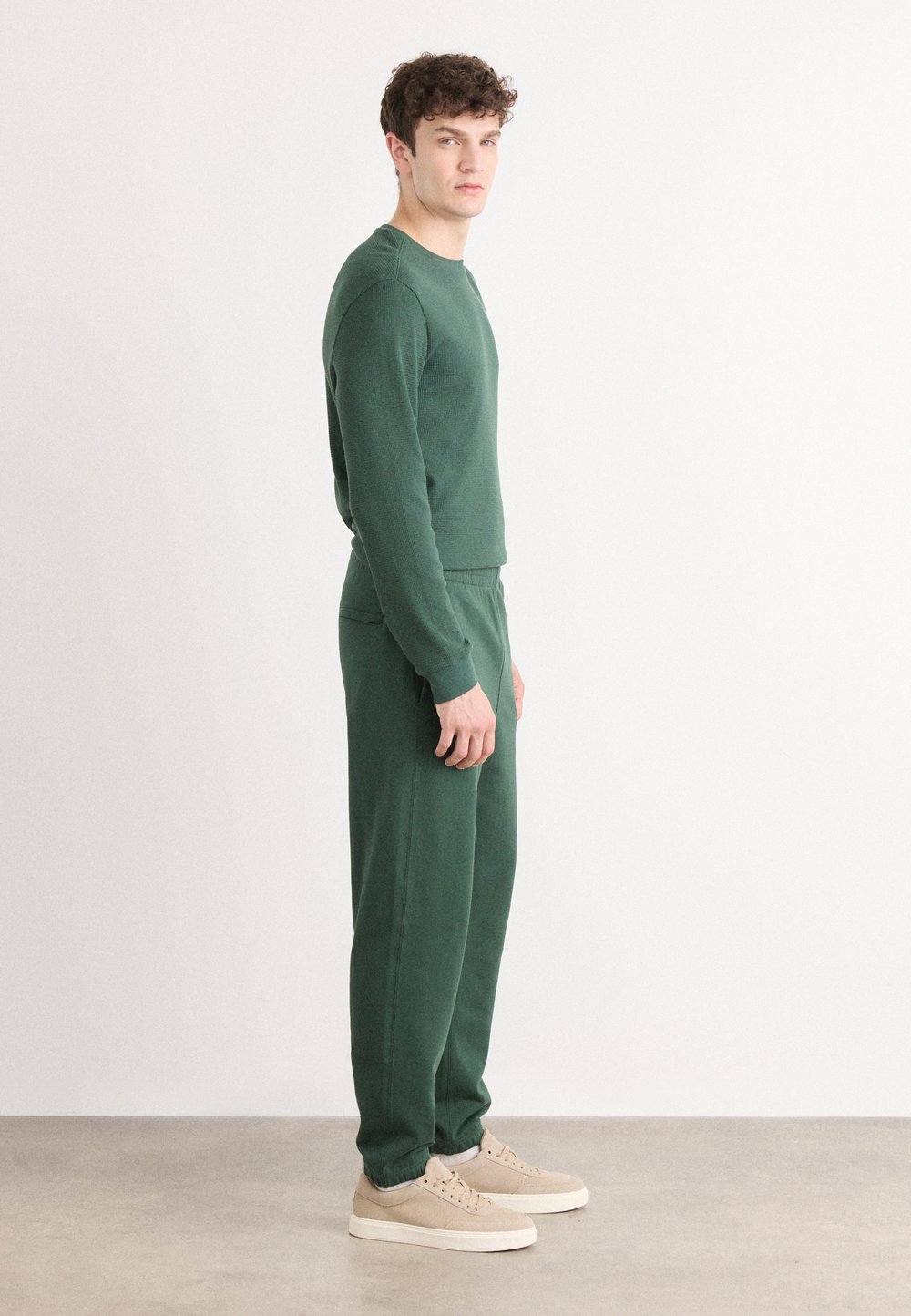 Green knitted sweatshirt and matching sweatpants, featuring a casual fit and ribbed texture, paired with light-coloured trainers.