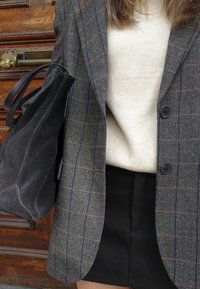 Szürke halszálka mintás zakó tengerészkék és barna kockás mintával, krém színű pulóverrel és fekete miniszoknyával párosítva. Fekete velúr táska bőr pánttal.