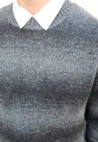 Pull en laine gris avec un motif en dégradé, doté d'un col côtelé et porté avec une chemise blanche à col en dessous. Texture douce, coupe décontractée.