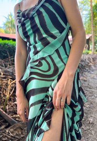 Robe sans manches en tissu bleu sarcelle avec de larges rayures marron, dotée de volants le long de l'ourlet et d'un détail orné à l'épaule.