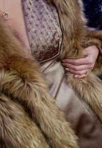 Brun pelscape over en satengkjole, med en utsmykket brodert livdel i en myk beige tone, glatt tekstur og metalliske aksenter.