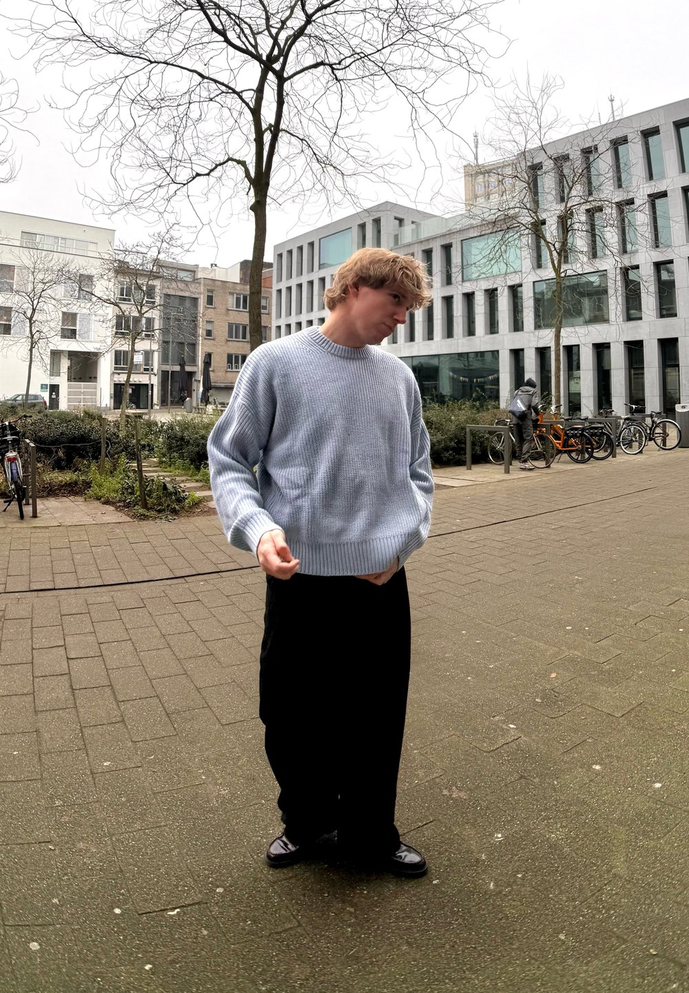 Ανοιχτό μπλε, υφασμάτινος πλεκτός σκούφος με χαμηλούς ώμους και ριγέ μανσέτες, σε συνδυασμό με μαύρο χαλαρό παντελόνι και σκούρα παπούτσια.