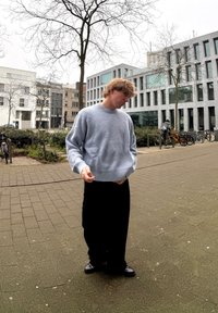 Ανοιχτό μπλε, υφασμάτινος πλεκτός σκούφος με χαμηλούς ώμους και ριγέ μανσέτες, σε συνδυασμό με μαύρο χαλαρό παντελόνι και σκούρα παπούτσια.