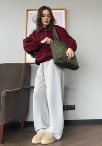 Bourgogne oversized sweatshirt, lysegrå joggingbukser og beige hjemmesko. Olivengrøn taske, glat tekstur, med et enkelt design.