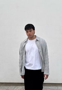 Jachetă matlasată de culoare albastru deschis, purtată peste un tricou alb, asociată cu pantaloni negri. Jacheta are un model texturat și o croială lejeră.