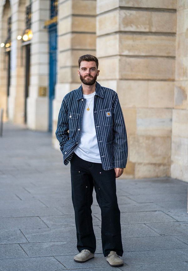Stripete denimjakke med en hvit t-skjorte under, svarte bukser og beige sko. Har to frontlommer og en avslappet passform.