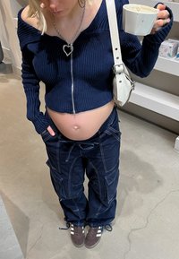 Marineblauw geribde cropped sweater met een voorrits, gecombineerd met donkerblauwe cargo broek met meerdere zakken en een trekkoord aan de broekspijpen.