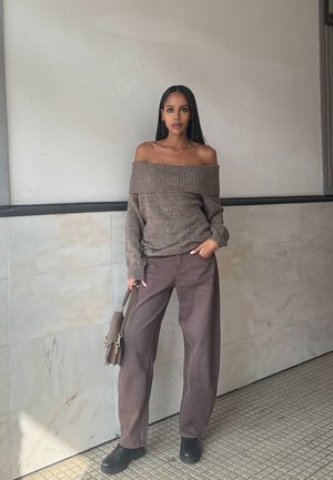 Jersey marrón off-the-shoulder, pantalones marrones holgados, zapatos negros y bolso marrón. Textura suave con detalles acanalados.