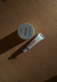 TOCOBO Multi Cream Glas und Bio Repair Gel Cream Tube, beide in Weiß mit rotem Text. Das Glas ist rund; die Tube ist schlank mit einem Drehverschluss.