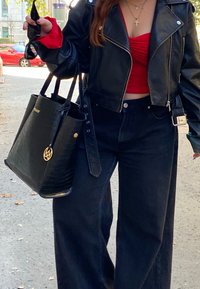 Μαύρο δερμάτινο cropped μπουφάν, κόκκινο εφαρμοστό τοπ, μαύρο παντελόνι ψηλής μέσης και μια υφασμάτινη μαύρη τσάντα με χρυσές λεπτομέρειες.