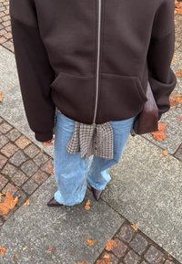 Tamsiai ruda užsegama su užtrauktuku su gobtuvu ir kišenėmis, šviesiai mėlynos plačios džinsinės kelnės, surištos patikrinimo rašto marškinėliais ties juosmeniu, ir violetiniai aštriais galiukais batai.