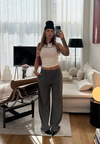 Biała ribrowana koszulka na ramiączkach z napisem "DICKIES", szare szerokie spodnie w prążki, czapka beanie w kolorze czarnym, uzupełniona burgundową torebką. Wnętrze.