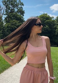 Roze geribbelde crop top en bijpassende hoge taille broeken, gedragen met zwarte zonnebril, buiten op een pad omringd door groen.