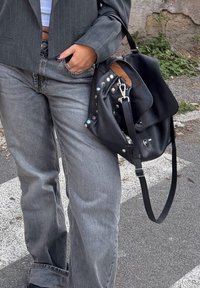Zwarte leren tas met een slouchy ontwerp, zilveren hardware en veelkleurige studs. Draag met grijze wijde jeans en een gestreepte blazer.