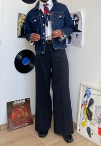 Denim jakna svetlo modre pranja, bela srajca, črne široke hlače in črne čevlje. Dopolnjena z vzorčeno ruto in očali.