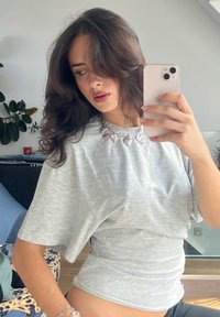 Hall rõngas T-särk lühikeste varrukatega, valmistatud pehmest materjalist, millel on hõbedane süda ripats. Sile tekstuur ja mugav disain.