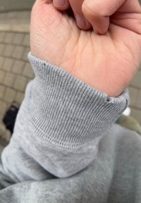 Γκρίζος σκούφος με ribbed υφή, απαλό ύφασμα και χαλαρή εφαρμογή, με ένα χέρι που φαίνεται εν μέρει από κάτω.