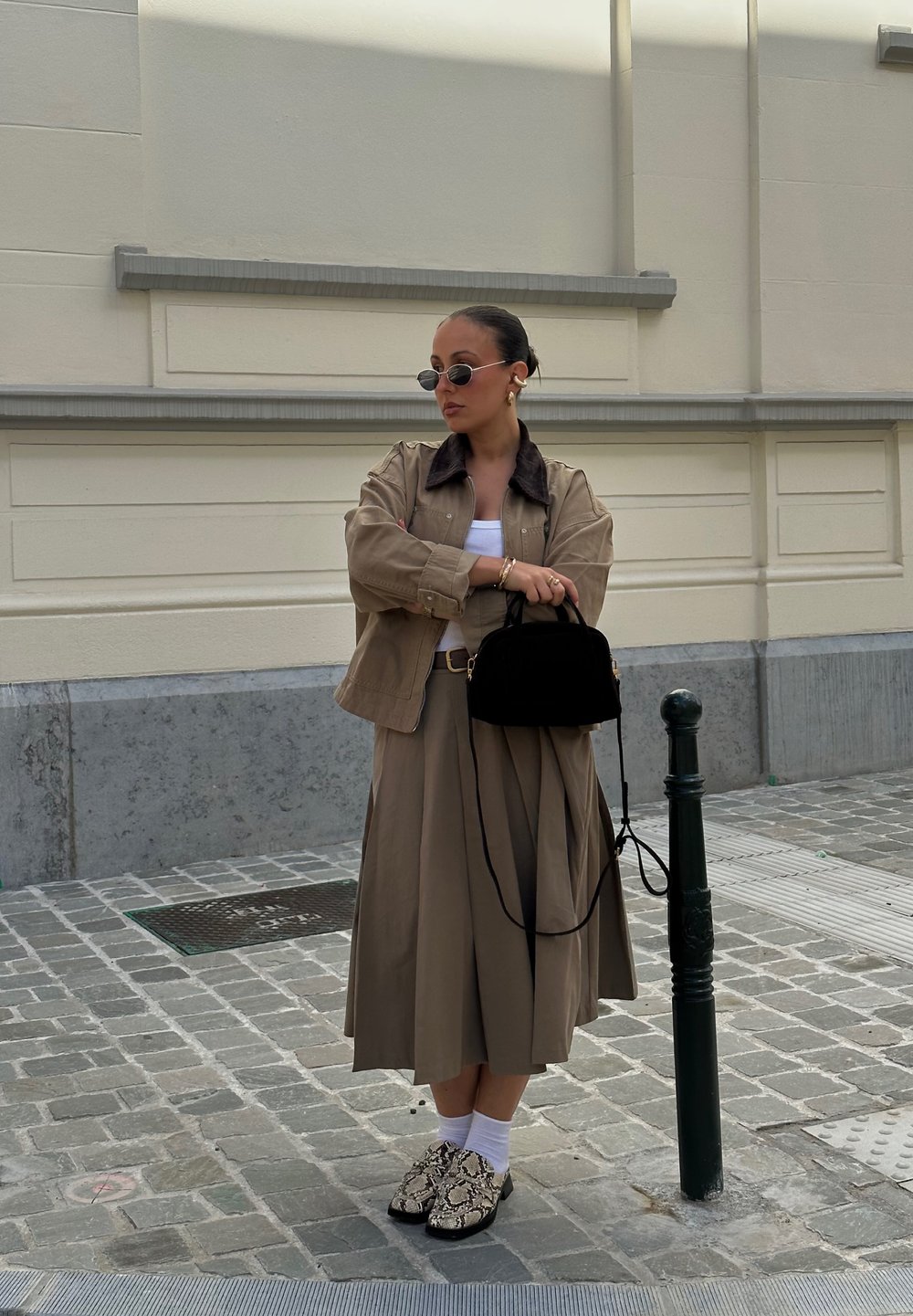 Bež jakk tumeda krae kohal valge pluusi ja pika bež seeliku peal. Must käs bag, valged sokid ja mustriga kingad, millel on reptiilide disain.