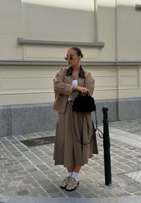 Bež jakk tumeda krae kohal valge pluusi ja pika bež seeliku peal. Must käs bag, valged sokid ja mustriga kingad, millel on reptiilide disain.