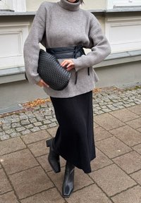 Grey ribbed sweater with high collar, black belted waist, textured woven clutch, black ribbed skirt, and square-toed black ankle boots.