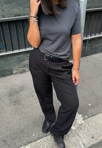 Sorte skreddersydde bukser med rett benpassform, sammen med en mørkegrå crewneck t-skjorte. Tilbehør inkluderer et svart belte og sølvarmbånd.