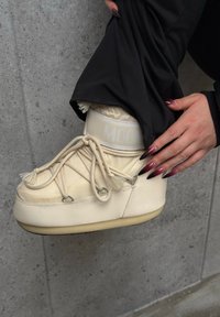 Buty w kolorze kremowym o teksturowanym wykończeniu, z frędzlami, elastycznym mankietem i dekoracyjnym sznurowaniem. Z akcentem w postaci białego logo.
