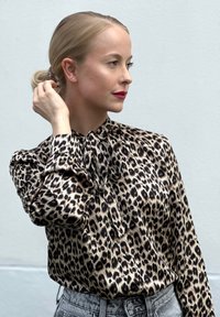 Μπλούζα με λεοπάρ μοτίβο από σατέν ύφασμα, διαθέτει φιόγκο στο γιακά, μακριά μανίκια και άνετη εφαρμογή, ταιριασμένη με ψηλοκάβαλο τζιν.