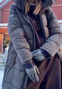 Manteau matelassé noir avec un design matelassé, une capuche et une doublure chaude. Gants noirs avec un détail accentué à carreaux sur les poignets.