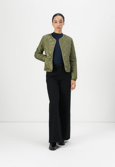 Chaqueta verde acolchada con cuello redondo, cierre a presión y bolsillos laterales, llevada sobre una blusa en tono marino y combinada con pantalones negros de pierna ancha.