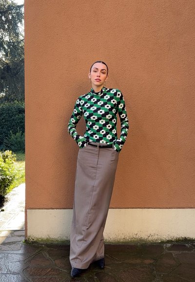 Top de cuello alto con flores verdes y mangas largas, combinado con una falda maxi gris, de corte ajustado y textura de tela suave.