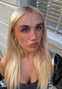 Blonde hair, smooth texture, and light streaks; silver earring; black top with metallic accents; warm skin tone; minimal makeup.