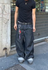 Mørke denim baggy jeans med rullede manchetter, kontrasterende sømmer, frontlommer og vedlagte nøkkelknippe; brukt med en svart t-skjorte.