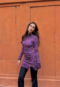 Robe longue à manches longues violette avec des rayures z ébrées noires, dotée d'un col montant et de fronces, associée à un pantalon noir ajusté.