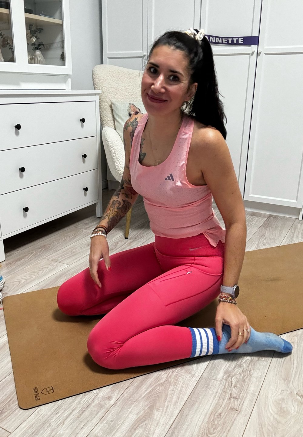 Top desportivo rosa com decote redondo, combinado com leggings rosa ajustadas com um bolso lateral. Meias azuis claras com riscas brancas.