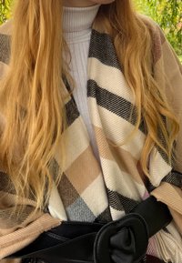 Enveloppé d'un motif à carreaux en beige, noir et blanc, avec une texture lisse, maintenu par une large ceinture noire à la taille.