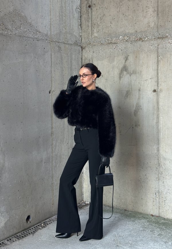 Musta tekoturkishame, korkeavyötäröiset mustat housut, mustat stiletto-korkokengät, pitkät nahkahanskat, pieni musta käsilaukku ja lasit.