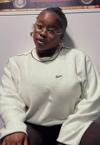 Sweatshirt de cor creme com um acabamento texturizado, apresentando um logótipo sutil em dourado. Mangas longas e largas com um design de decote contrastante.