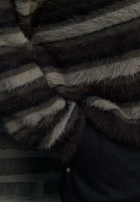 Pull rayé marron et beige en matière duveteuse, avec une coupe ample et une finition texturée. Associé à un tissu en denim foncé.