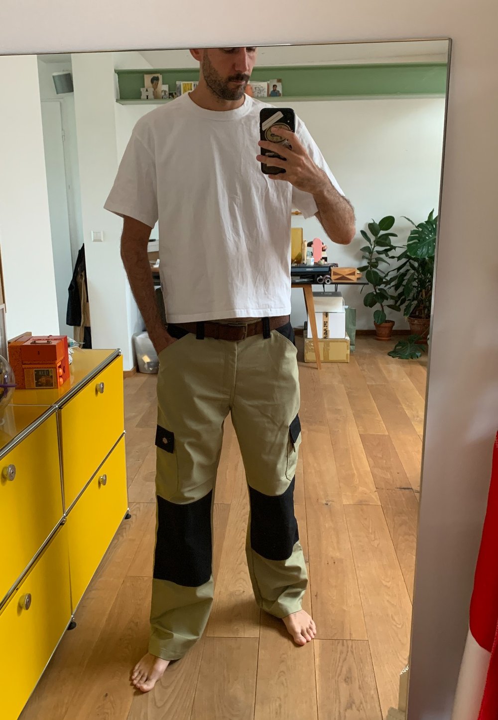 Cargo pants in lichtgroen met zwarte accenten. Losse pasvorm, meerdere zakken, zichtbare stiksels. Draagt met een eenvoudig wit T-shirt.