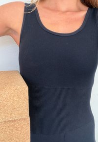 Czarny prążkowany top na ramiączkach o dopasowanym kroju i szerokich szelkach. Tkanina ma gładką fakturę z teksturowanym paskiem w talii.