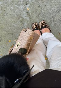 Borsa beige testurizzata con motivo a coccodrillo e rifiniture dorate, abbinata a ballerine con stampa leopardata nera e beige e pantaloni color crema.