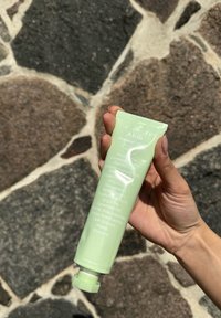 Tube vert de la crème Abib Heartleaf, compressible, avec du texte blanc et un bouchon. L'arrière-plan montre une surface en pierre texturée.