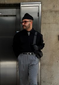 Μαύρος πουλόβερ με γιακά, γκρι πλεκτές παντελόνες, μαύρα γάντια και μια τσάντα. Στρογγυλά γυαλιά ηλίου και ένα πλεκτό σκουφάκι ολοκληρώνουν την εμφάνιση.