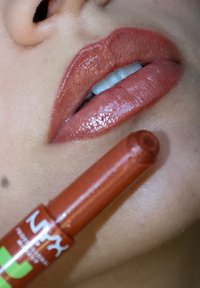 NYX leppeprodukt i en blank, kobber-rød nyanse med en glatt tekstur, med en rund tupp og en grønn logo på et rødlig rør.