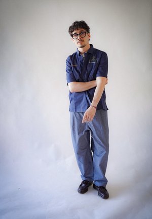 Camisa de manga corta en color navy con detalles bordados, combinada con pantalones holgados de color azul claro y zapatos oscuros. Diseño sencillo y tejido suave.