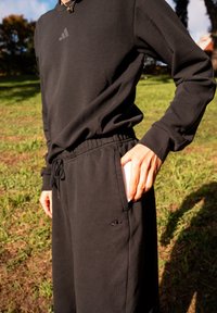 Black athletic long-sleeve top with a subtle logo, paired with matching black joggers featuring an embroidered logo and an elasticated waistband.