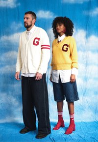 White cardigan with red accents and "G" logo, teamed with dark wide-leg trousers. Yellow jumper featuring "G" logo, denim shorts, and red shoes.