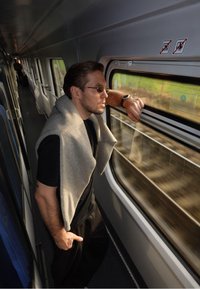 Hall nahast sall, mis on lahtiselt heidetud musta särgi peale ja mida kannab inimene, kes toetub rongiaknale. Näha on päikeseprille ja kella.