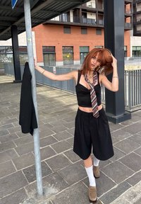 Crne kratke hlače visokog struka, tijesni crni top s čvorom sprijeda, uzorčana kravata, bijele čarape i smeđe cipele. Crni sako objesiti na štapu.