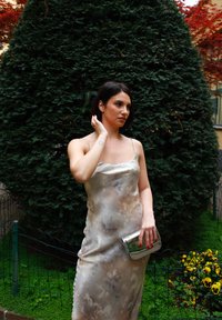 Ρευστό, χωρίς μανίκια φόρεμα σε απαλά, ήσυχα χρώματα με μοτίβο υδατογραφίας. Συνδυασμένο με έναν κομψό ασημένιο φάκελο. Πλούσιο πράσινο φόντο.